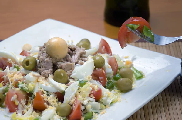 Plato de ensalada con un tenedor con tomate y pimiento