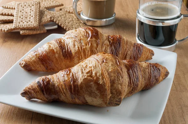 Croisanes y galletas en una mesa con tazas de caf