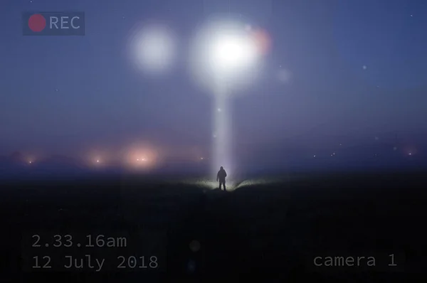 Turvakameran Kuva Siluetoidusta Hahmosta Seisomassa Sumuisella Pellolla Yöllä Katselemassa Ufoa — kuvapankkivalokuva