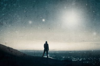 Gökyüzünde UFO izlerken tepede yalnız kukuletalı şekil ayakta