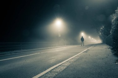 Yalnız bir kukuletalı adam sisli bir yolun ortasında bir grunge ile gece resmini vintage duo sesi değiştir - ayakta