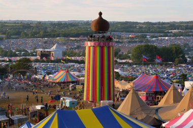Glastonbury Festivali 06.27.2015. Arasında Glastonbury festivalinde şerit Tower'da diğer sahne ve piramit sahne güneşli bir akşam mesafe seyir.