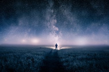Bir adam silüeti Photoshop'ta bir alanda bir meşale ışıklarda ufukta huysuz bir gece üzerinde seyir ile düzenlenmiş bir dijital sanat resim. Yıldız ek yükü bir galaksi ile. 