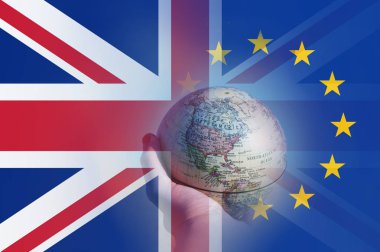 Brexit kavramı. Kuzey Amerika üzerinde odaklanan bir küre tutan bir el. Union Jack ve E.U üzerinde bayrakları taşıyan üst üzerinde katmanlı. 