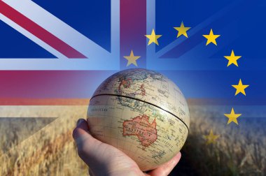 Brexit kavramı. Avustralya, Yeni Zelanda ve Se Asya yaz buğday ve arpa alanında gösterilen bir küre tutan bir el. Union Jack ve E.U üzerinde bayrakları taşıyan üst üzerinde katmanlı. 