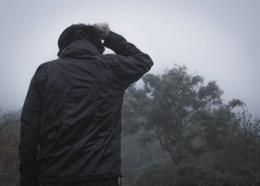 Sisli, yağmurlu bir günde yalnız ürkütücü kukuletalı şekil ayakta kırsal bir yolda. İle sessiz, grenli Düzenle.