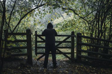 Bir kapı bir ormanda yalnız kapşonlu ürkütücü şekil beklemede Güz.