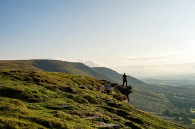 Bir dağ kenarında duran, karşısında bakan bir adam bir 