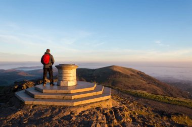 Worcestershire Beacon, Malvern Hills, Worcestershire, Puslu kış sunsrise zirvesine üzerinde duran bir yalnız uzun yürüyüşe çıkan kimse. İngiltere.