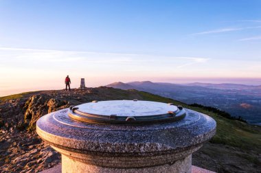 Bir uzun yürüyüşe çıkan kimse Worcestershire Beacon, üst üzerinde bir puslu, toposcope adlı bir kış sabahı gündoğumu. Malvern Hills, İngiltere.