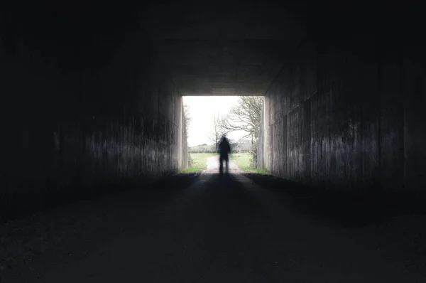 Una silueta fantasmal borrosa de pie en el borde de un túnel espeluznante —  Fotos de Stock