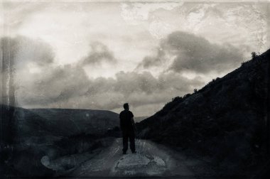 Gizemli, huysuz bir dağ yolunda ki tepeye bakan yalnız bir yürüyüşçü. Karanlık, grunge, vintage bir edit ile.