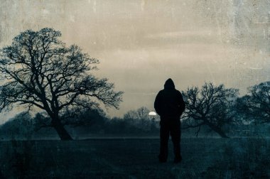 Kışla öğleden sonra gün batımını izlerken, bir rakam ayakta alan bir ürkütücü silüet. Grunge, Grainy, Vintage Edit ile.