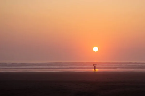 Une silhouette d'une femme portant une planche de surf sur sa tête alors qu'elle sort de la mer — Photo