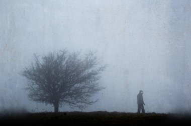 Kışın bir ağacın yanında parlayan gözleri olan ürkütücü, siluetli bir figür. Dokulu, yıpranmış vintage düzenleme ile.