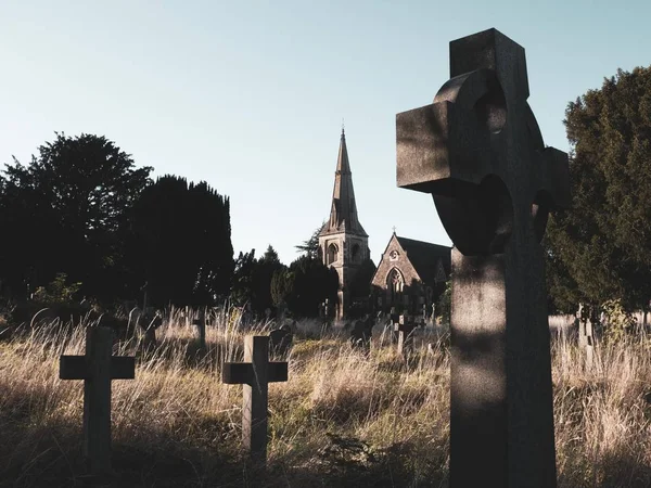 Een spookachtig, griezelig, overwoekerd kerkhof met een kerk op de achtergrond — Stockfoto