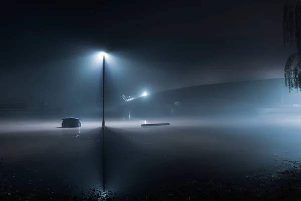 A street light standing in flood water with a bridge at night — Stock Photo, Image
