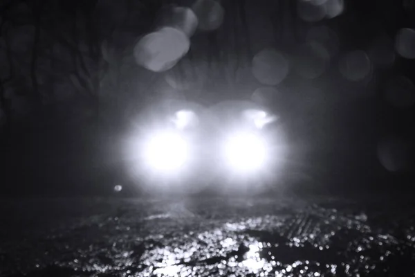 A low angle shot of car headlights on a winters night in the countryside. With a blurred, out of focus edit.