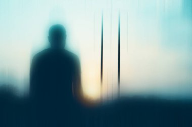 Gizemli bir erkek figürü, güneş tarafından silueti oluşturulmuş. Bulanık, bulanık bir düzenleme ile.                 