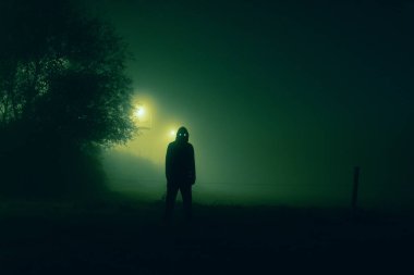 Parlayan gözlü, tehditkar doğaüstü bir şahsiyet kırsalda sisli, ürkütücü bir gecede siluetlendi.
