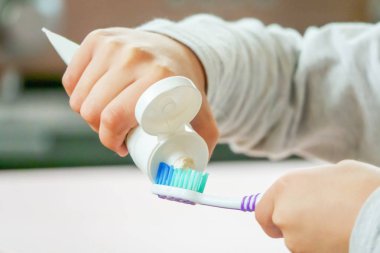 Çocuk bulanık arka plan üzerinde diş fırçası ve diş macunu uygulamak
