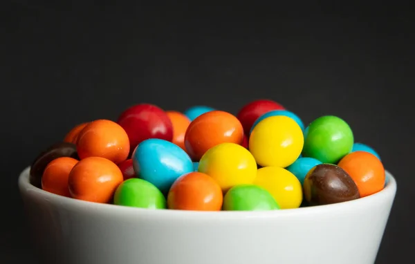 Primer plano de una pila de caramelos recubiertos de chocolate de colores, fondo de chocolate —  Fotos de Stock