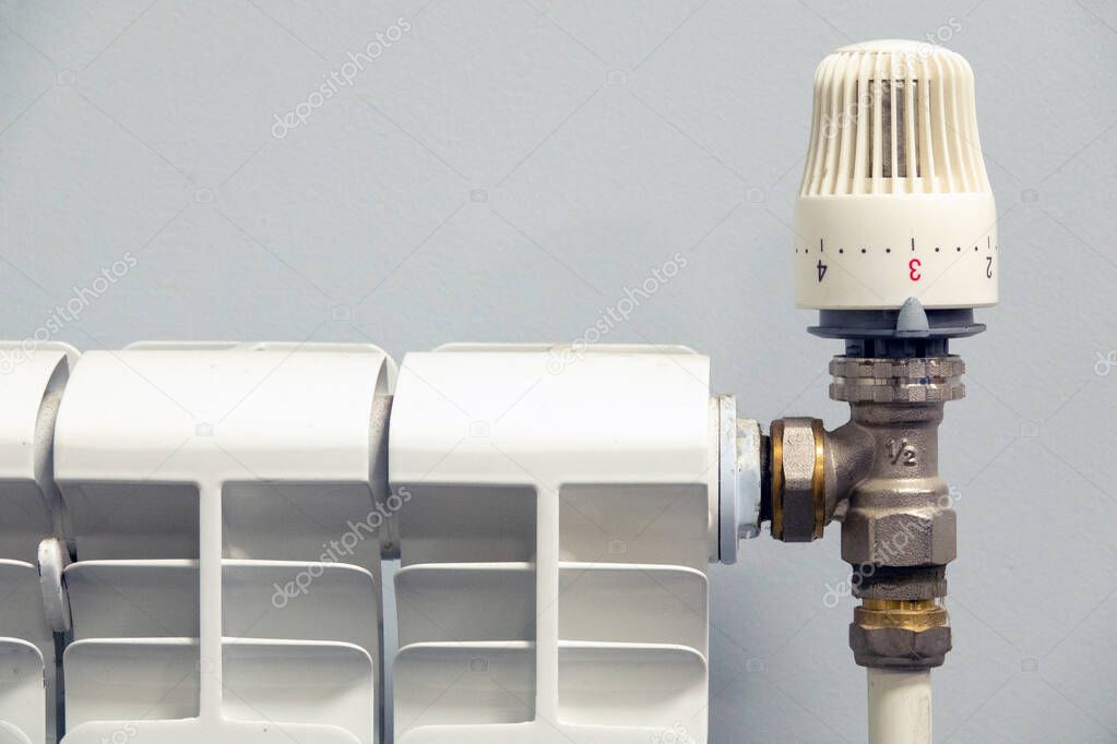 Thermostatic valve on a radiator on gray background