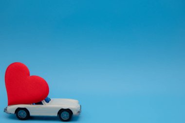 Beyaz eski model oyuncak araba pembe arka planda bir buket çiçek getiriyor. 14 Şubat, Sevgililer Günü kartpostalı. Çiçek teslimatı. 8 Mart, Uluslararası Mutlu Kadınlar
