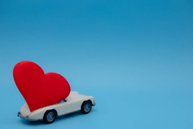 Beyaz eski model oyuncak araba pembe arka planda bir buket çiçek getiriyor. 14 Şubat, Sevgililer Günü kartpostalı. Çiçek teslimatı. 8 Mart, Uluslararası Mutlu Kadınlar