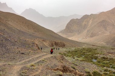 Dağlara giden tozlu bir yol. Tacikistan 'da Murghab yakınlarında sis ve dağlar.