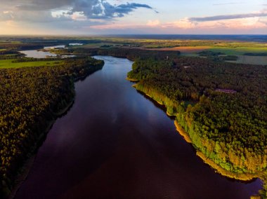 Fırtınalı gökyüzü gün batımında arka planda güzel bir orman gölünde scooterlı..