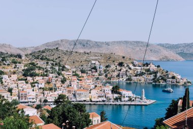 Symi Adası, Yunanistan - Haziran 2018 yaklaşık: hava görünümünü deniz ve liman ve cascade tepe üzerinde parlak binaların güneşli bir Symi Adası Yunanistan.