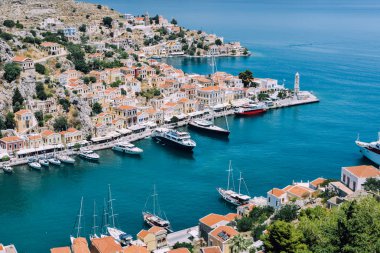 Symi Adası, Yunanistan - Haziran 2018 yaklaşık: hava görünümünü deniz ve liman ve cascade tepe üzerinde parlak binaların güneşli bir Symi Adası Yunanistan.
