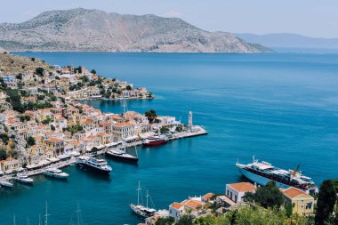 Symi Adası, Yunanistan - Haziran 2018 yaklaşık: hava görünümünü deniz ve liman ve cascade tepe üzerinde parlak binaların güneşli bir Symi Adası Yunanistan.