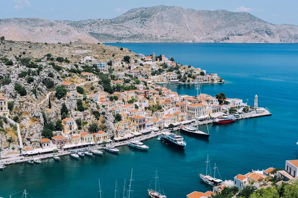 Symi Adası, Yunanistan - Haziran 2018 yaklaşık: hava görünümünü deniz ve liman ve cascade tepe üzerinde parlak binaların güneşli bir Symi Adası Yunanistan.