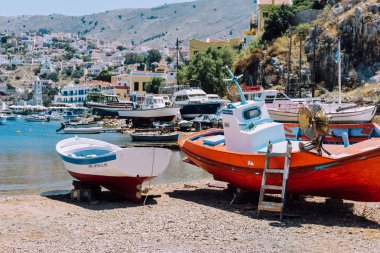 Symi Adası, Yunanistan - Haziran 2018 yaklaşık: sahil Symi Adası ve tepeler gemilerde Yunanistan güneşli bir arka plan üzerinde renkli evleriyle.