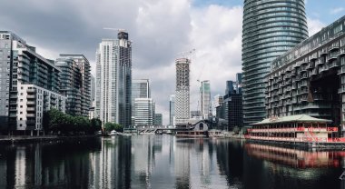 Londra, Ingiltere-Circa Haziran 2019: bulutlu gökyüzü ile güneşli bir gün Londra Canary Wharf finans bölgesinde cam binalar cepheleri ile modern mimari.