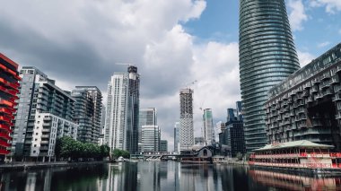 Londra, Ingiltere-Circa Haziran 2019: bulutlu gökyüzü ile güneşli bir gün Londra Canary Wharf finans bölgesinde cam binalar cepheleri ile modern mimari.