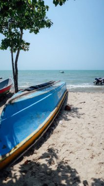 RINCON DEL MAR, COLOMBIA - CIRCA FEBRUARY 2020: Sahilde beyaz kumlu balıkçı tekneleri ve kıyıdaki küçük bir köyde Karayip denizinin mavi suları.