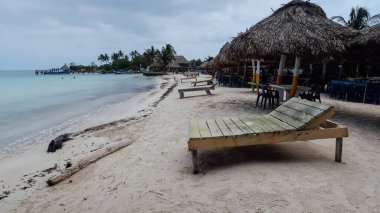 RINCON DEL MAR, COLOMBIA - CIRCA FEBRUARY 2020: San Bernardo Takımadası tropikal adası Tintipan 'da Karayip denizinin turkuaz mavi sularıyla plajda ahşap güneş yatakları.