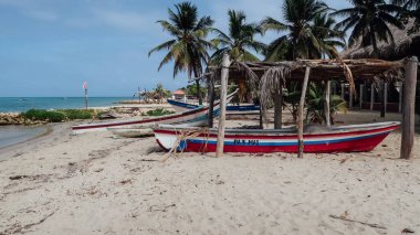 RINCON DEL MAR, COLOMBIA - CIRCA FEBRUARY 2020: Sahilde beyaz kumlu balıkçı tekneleri ve kıyıdaki küçük bir köyde Karayip denizinin mavi suları.