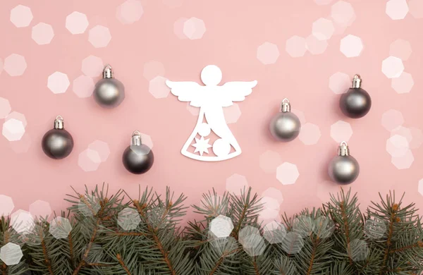 Pearl Christmas balls and figure of angel on the pink background with pine tree branches