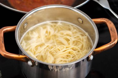 Mutfaktaki elektrikli ocakta tavada spagetti haşlıyorum.