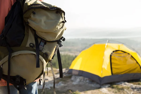 Big camping backpack and yellow tent.