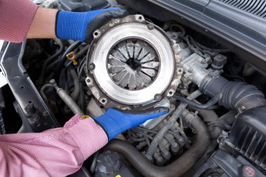 Otomatik mekanik koruyucu iş eldiven giymiş eski debriyaj sepeti bir araba motoru üzerinde tutar.