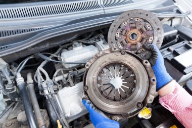 Otomatik mekanik eski Debriyaj sepeti ve plaka üzerinde bir araba motoru tutan koruyucu iş eldivenler