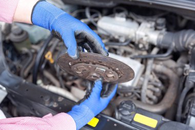 Otomatik mekanik koruyucu iş eldiven giymiş eski debriyaj disk üzerinde bir araba motoru tutar.