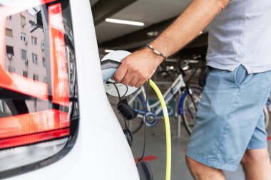 Bir elektrik elektrikli araç şarj için eklenti tutan el
