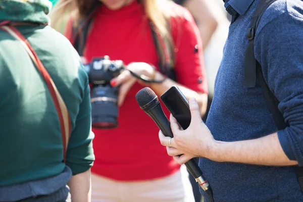 Reporter at media event holding microphone, blurred female photo — Stock Photo, Image
