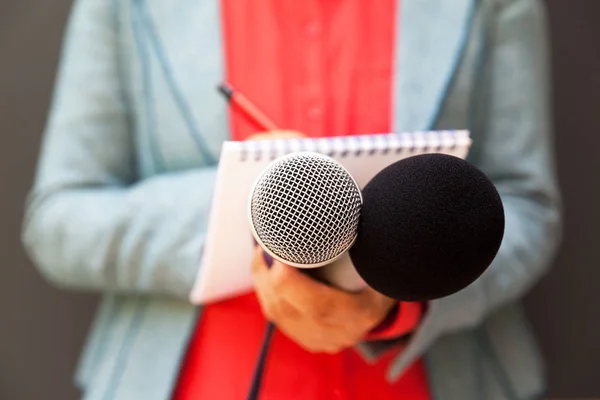 Journaliste féminine lors d'une conférence de presse, écrivant des notes, tenant un microphone — Photo